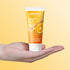 Bright orange Vitamin C face wash tube displayed on a vibrant yellow background for glowing skin.